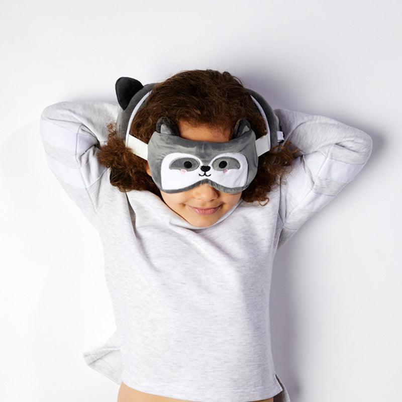 Child wearing a raccoon sleep mask and neck pillow.